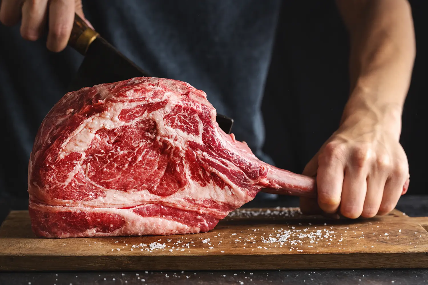 butcher-cuting-fresh-appetizing-tomahawk-steak-old-wooden-board-closeup butcher-cuting-fresh-appetizing-tomahawk-steak-old-wooden-board-closeup